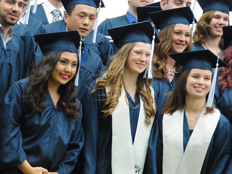 graduates posing in their caps and gowns before commencement ceremonies